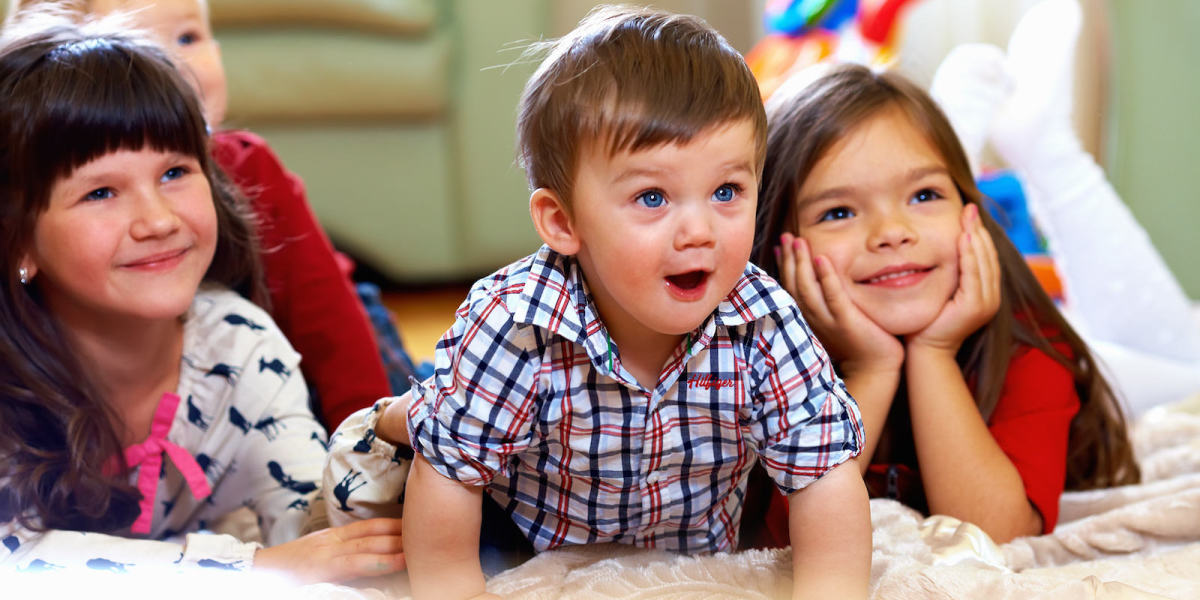 group of happy kids watching tv at home